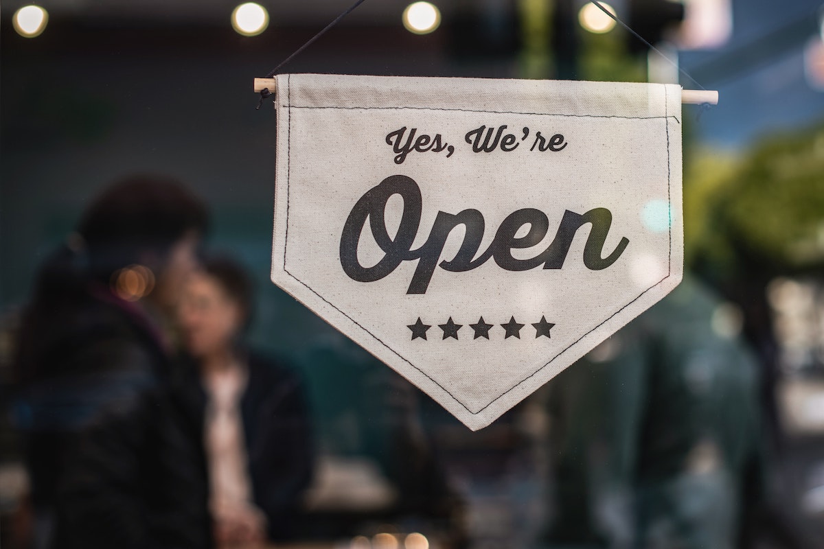 A Small Banner Sign in a Shop Window Reads Yes We're Open Salsify How to Implement an Omnichannel Retail Stratrgy