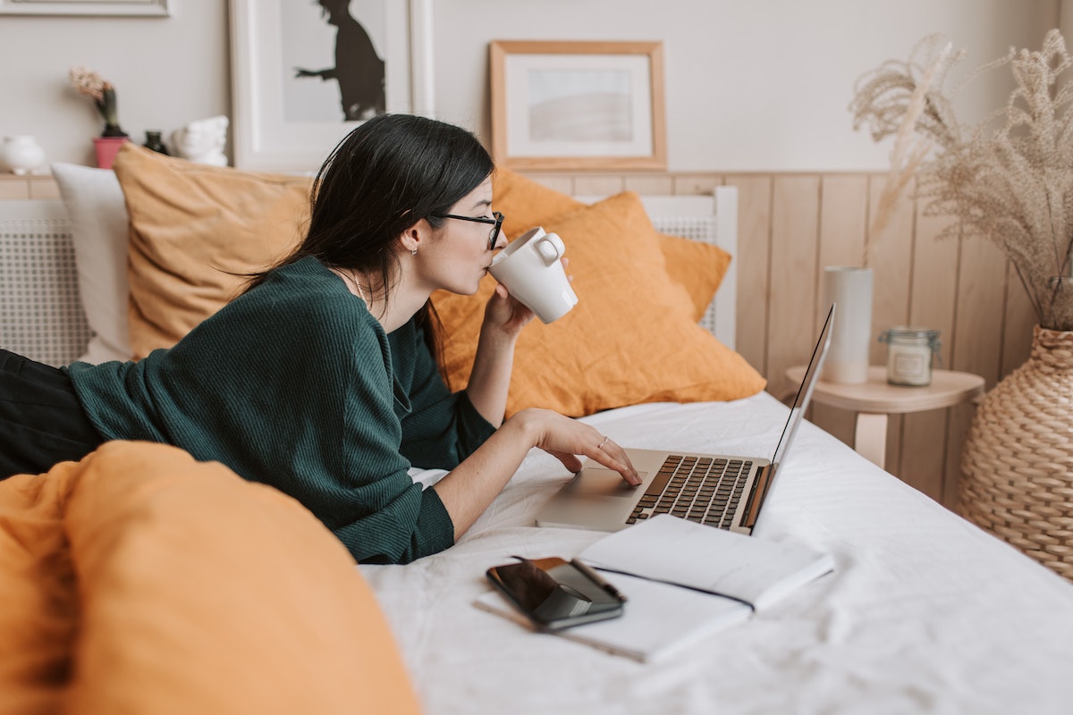 A Woman Drinks Coffee and Works on Her Laptop in Bed Salsify Digital Shelf